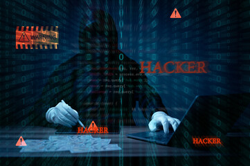 A Hacker is typing on a laptop and touch tablet with the words Hacker written on the screen....
