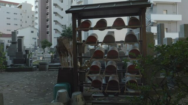 Watering buckets at Traditional Japanese Cemetery in Fukuoka with Rows of Stone Lantern