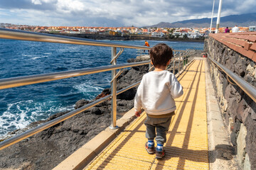 Boy smiling on summer seaside vacation by the sea, going down towards the water