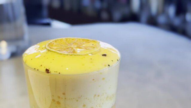 Close-up of a refreshing citrus smoothie with a dried orange slice and black specks, served in a glass.