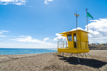 Fototapeta na wymiar Yellow lifeguard tower in California with green flag