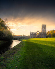 Fountains Abbey at Sunset: A historic masterpiece bathed in the warm glow of twilight, reflecting serenity and grandeur.