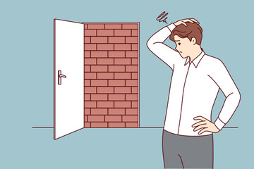 Business man is at dead end, looking for way to solve situation, standing near door blocked with bricks. Dead end as metaphor for obstacle on path to success, and problem of overcoming obstacles