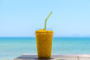 Smoothie made from fresh mango fruits and passion fruits with sea and sky background.