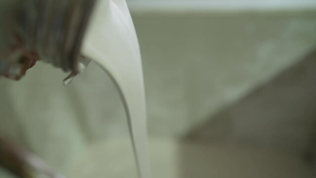 Production of liquid construction mixtures at a factory, close-up. Ceramic laboratory. A beige liquid mixture is poured.