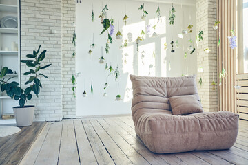 Interior design of room with soft sofa, artificial flowers levitating, hanging flowers on a white background, white wall with window shadow. Background with copy space. Template for your design.