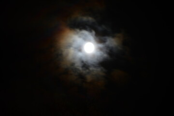 Fototapeta na wymiar Full moon shining through clouds