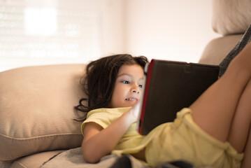 little girl looking digital tablet at home