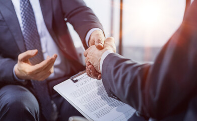 Close-up of two business people shaking hands while sitting at the working place.