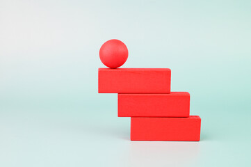 Red wooden ball on top of stacked red blocks.