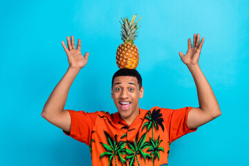 Photo of excited funky guy dressed print shirt holding head pineapple isolated blue color background