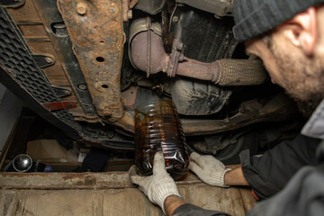 Black motor oil is drained under the car in a pit in the garage. Car maintenance in the garage with...