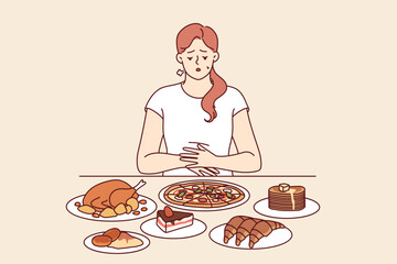 Problem of overeating in woman sitting at table with fast food, and in need of balanced diet. Girl feels heaviness in stomach due to regular overeating, which causes deterioration of immune system.