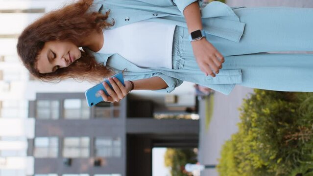 Tourist traveler preteen child kid using smartphone typing text messages looking for search a way on map in mobile navigator app outdoors. Girl walking passes by urban city street background. Vertical