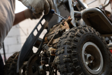 An ATV being repaired by an unqualified mechanic in a garage. A mechanic tightens a part on an ATV...