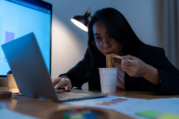 The young woman worked late and is now eating instant noodles at the office