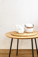 Wooden table with ceramic tea or coffee pottery set against white wall. Vertical with copy space.