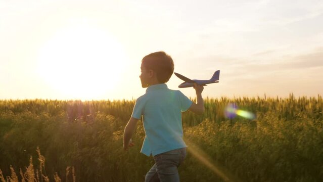Authentic child running down a country road playing with an a plane. Funny boy running against nature sunset background bouncing jumping up