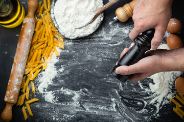 Hand holding wooden grinder. Preparation pasta, pizza, bread on black background.