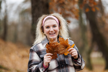 Woman Holding a Leaf and Smiling at Camera With Braces