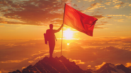 A man is standing on a mountain peak holding a red flag. The flag is waving in the wind, and the sun is setting in the background. Concept of triumph and accomplishment