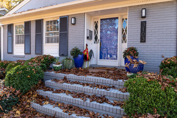 Front porch and stairs of house covered deeply in fall leaves, home maintenance leaf clean up,...