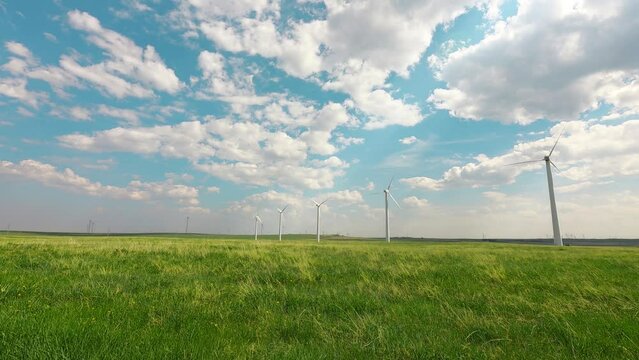 time-lapse wind turbine on a field green field with heavenly fluffy clouds soft blue sky background. clean energy is produced from natural sources like sunlight, and wind. green environment concept.