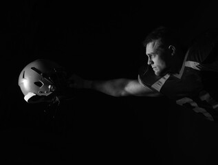 American football player on a dark background in black and orange equipment.