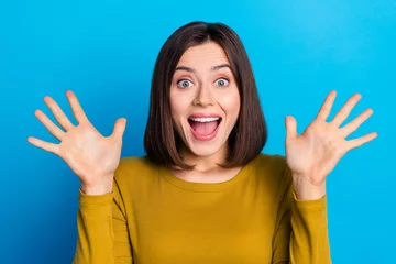 Tuinposter Photo of excited cheerful woman wear shirt smiling open mouth rising arms palms isolated blue color background © deagreez