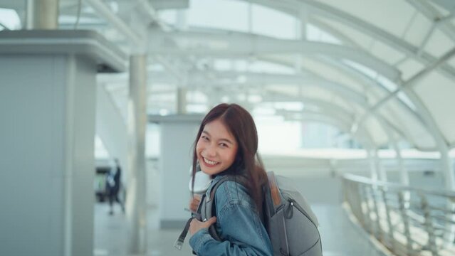Happy asian tourist woman wearing headphones and camera on her neck and backpack walking in the city, Female enjoying city life, Slow motion
