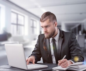 Naklejka premium Young successful businessman at workplace with laptop