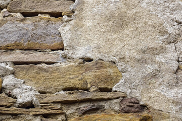Texture of old stone wall with collapsed plaster. Background of shabby building surface. Destroyed wall with fallen plaster. Weathered surface. Copy space. Selective focus.