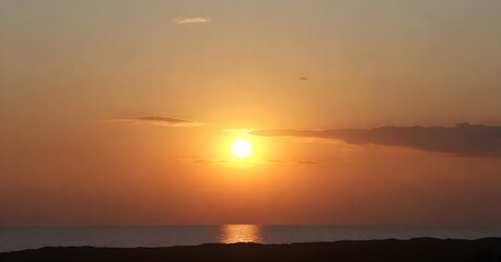 Fototapeta premium Stunning landscape of a golden sun setting over the horizon of a tranquil blue ocean