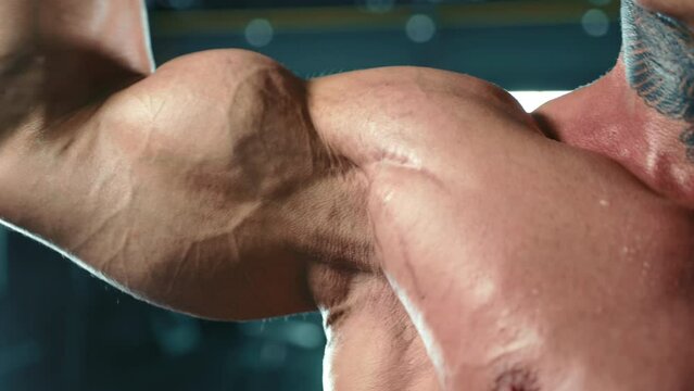 The camera zooms in on a man's flexed bicep as he performs a bicep curl, showcasing the impressive muscle definition and strength of a dedicated athlete. Camera 8K RAW. 