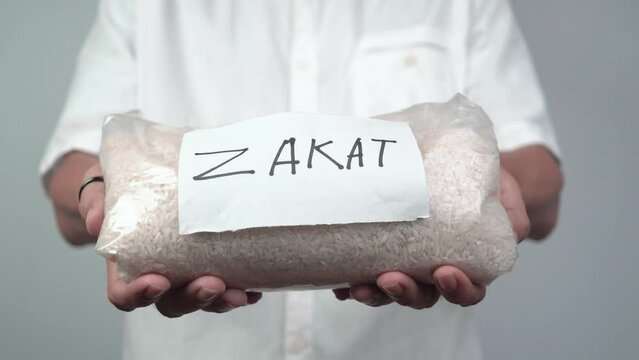 a muslim man holds a bag of rice for zakat. bags of rice with zakat written on them to help the poor in Islamic worship. Concept of Islamic charity during Ramadan