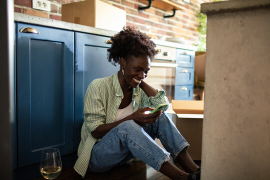 Woman using smartphone on floor with moving boxes around
