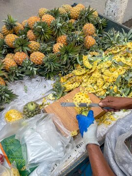 cutting and selling fresh pineapple slices on street food fruit stall in Chittagong, Bangladesh