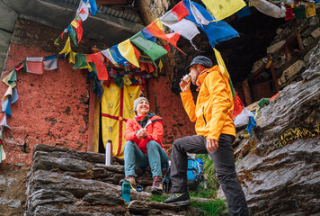 Chatting smiling Backpackers Couple tea break at small sacred Buddhist monastery decorated...