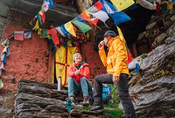 Crédence de cuisine en verre imprimé Makalu Chatting smiling Backpackers Couple tea break at small sacred Buddhist monastery decorated multicolored Tibetan prayer flags with mantras. Climbing Mera peak route in Makalu Barun National Park, Nepal