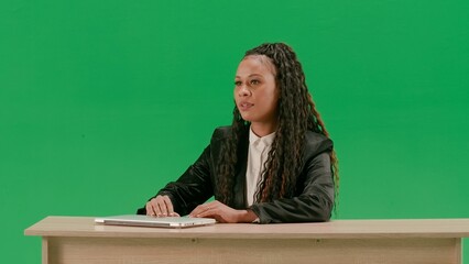 Female reporter at the desk isolated on chroma key green screen background. African american woman...