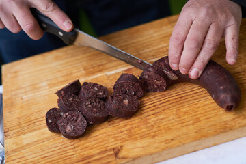 Close view of the hands cutting blood sausage with a knife