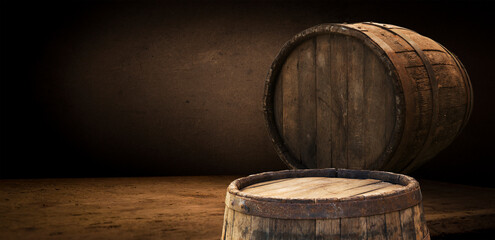 Two hardwood barrels are displayed on a wooden table at a winery event. The flash photography highlights the natural materials tints and shades in contrast with the darkness surrounding them - 773333852