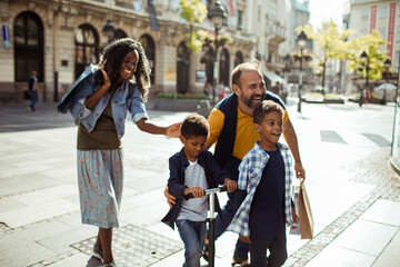 Happy family walking together on a city street with two children