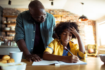 Father helping son with homework in kitchen - obrazy, fototapety, plakaty