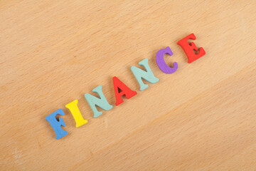 FINANCE word on wooden background composed from colorful abc alphabet block wooden letters, copy space for ad text. Learning english concept.