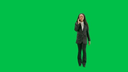 Young female reporter isolated on chroma key green screen background. Full shot african american woman tv news host walking and talking on smartphone.