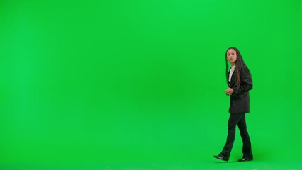 Young female reporter isolated on chroma key green screen background. Full shot african american woman tv news host talking showing advertisement area.