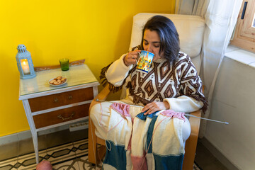 Middle aged woman knitting wool drinking from a modern mug