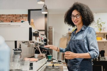 Smiling african young female barista bartender waitress making coffee using coffee machine in cafeteria, brewing drip filter from quality beans in restaurant coffee shop