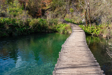 Enchanting hiking trail on rustical wooden footpath in magical Plitvice lakes National Park, Karlovac, Croatia, Europe. Walking over turquoise colored water in natural idyllic landscape. Wanderlust